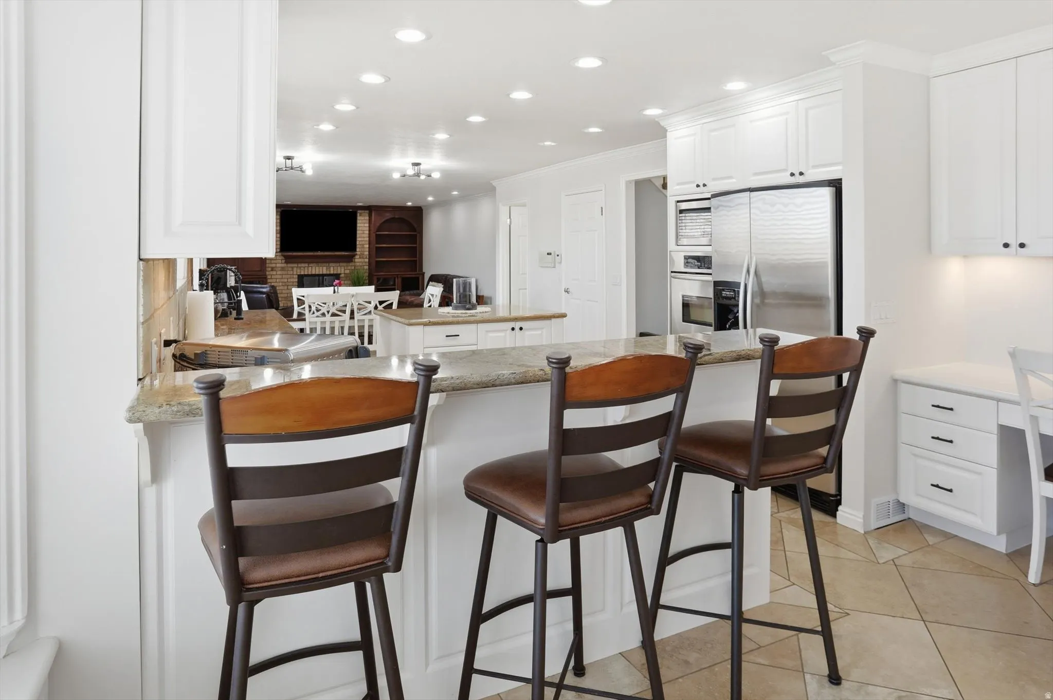 Kitchen with a center island, white cabinets, stainless steel appliances, decorative backsplash, and a kitchen bar