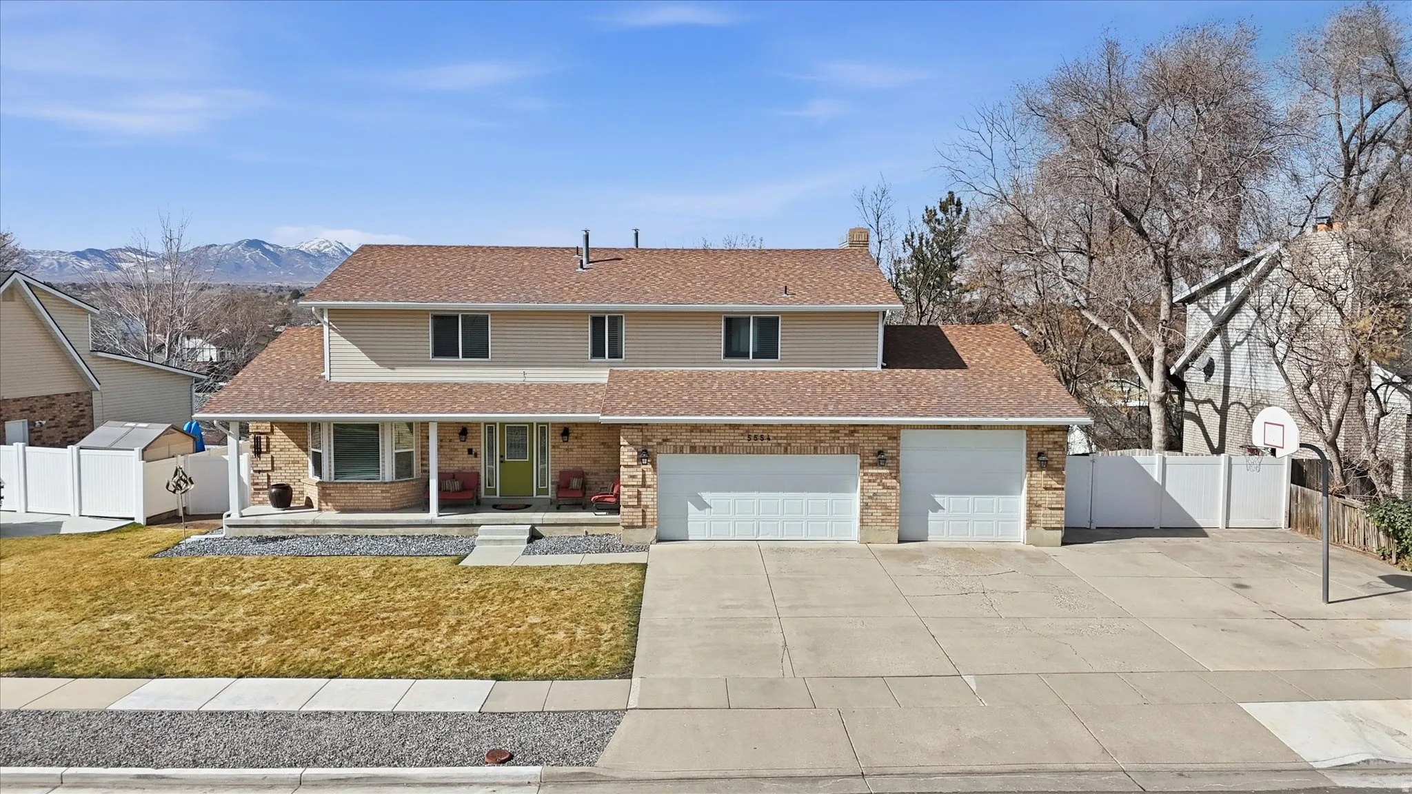 Traditional home featuring covered porch, concrete driveway, brick siding, an attached garage, and a chimney