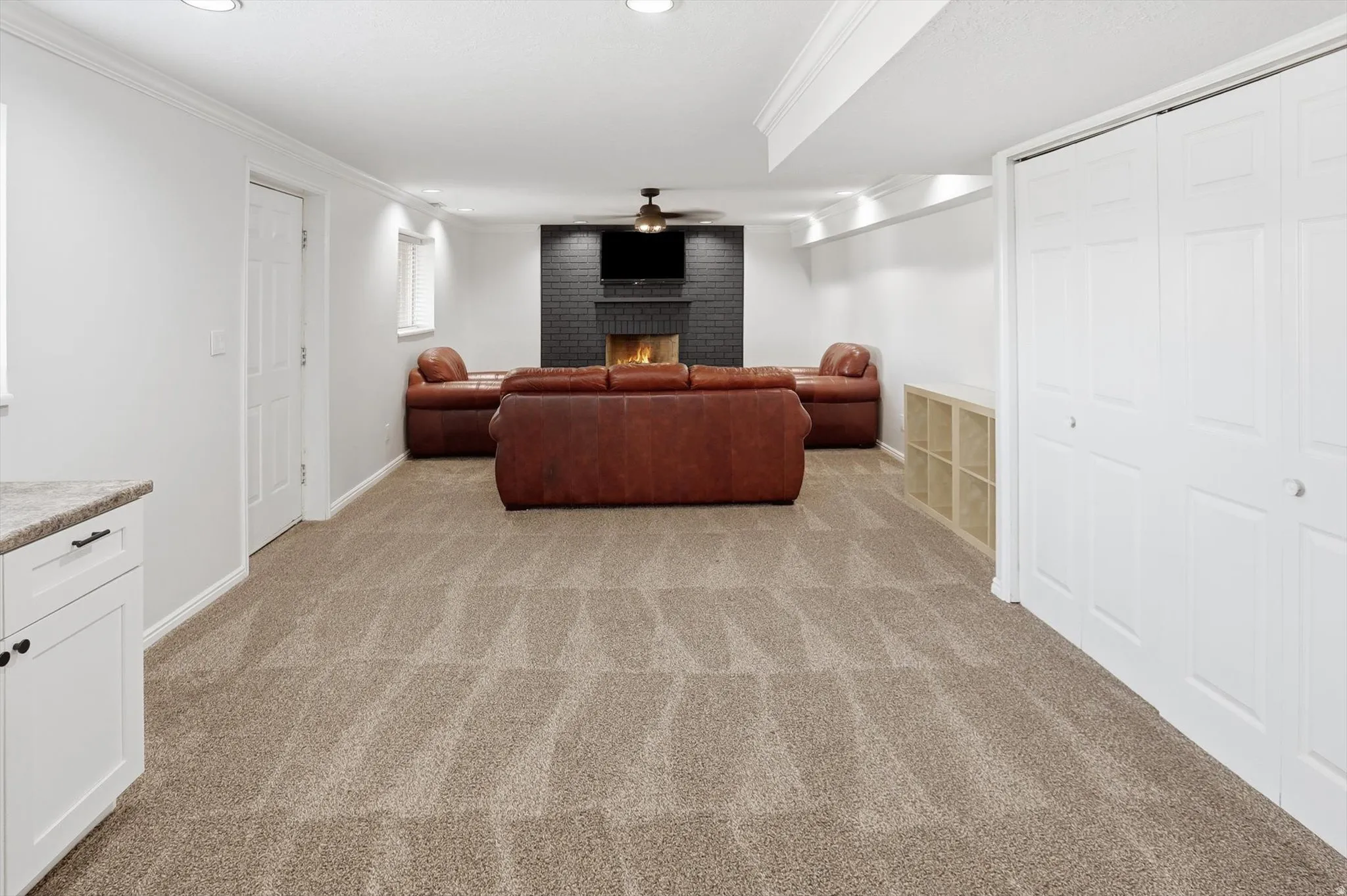 Living room featuring crown molding, light carpet, a fireplace, ceiling fan, and recessed lighting