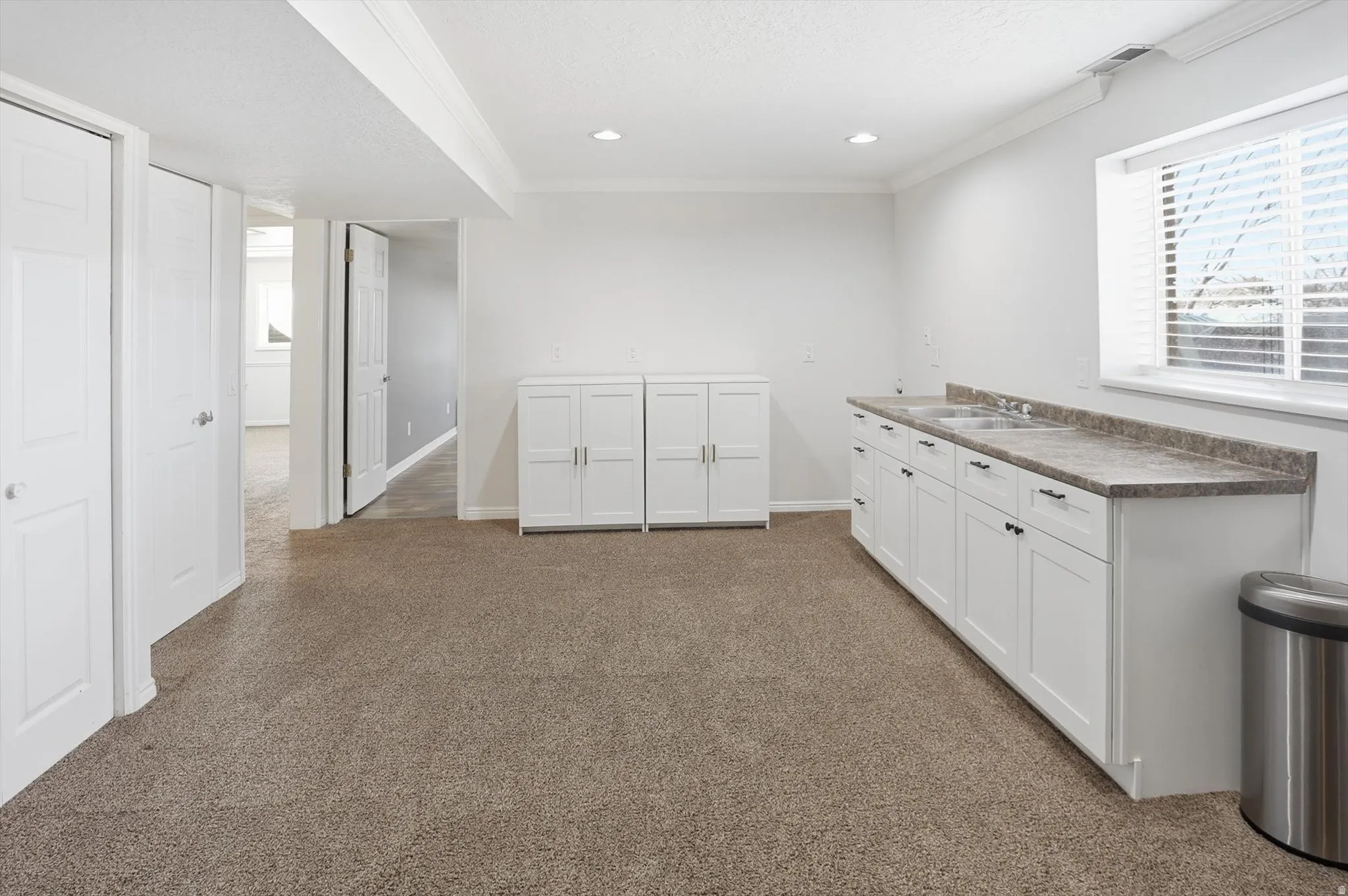 Kitchen with white cabinetry, crown molding, dark carpet, recessed lighting, and dark countertops