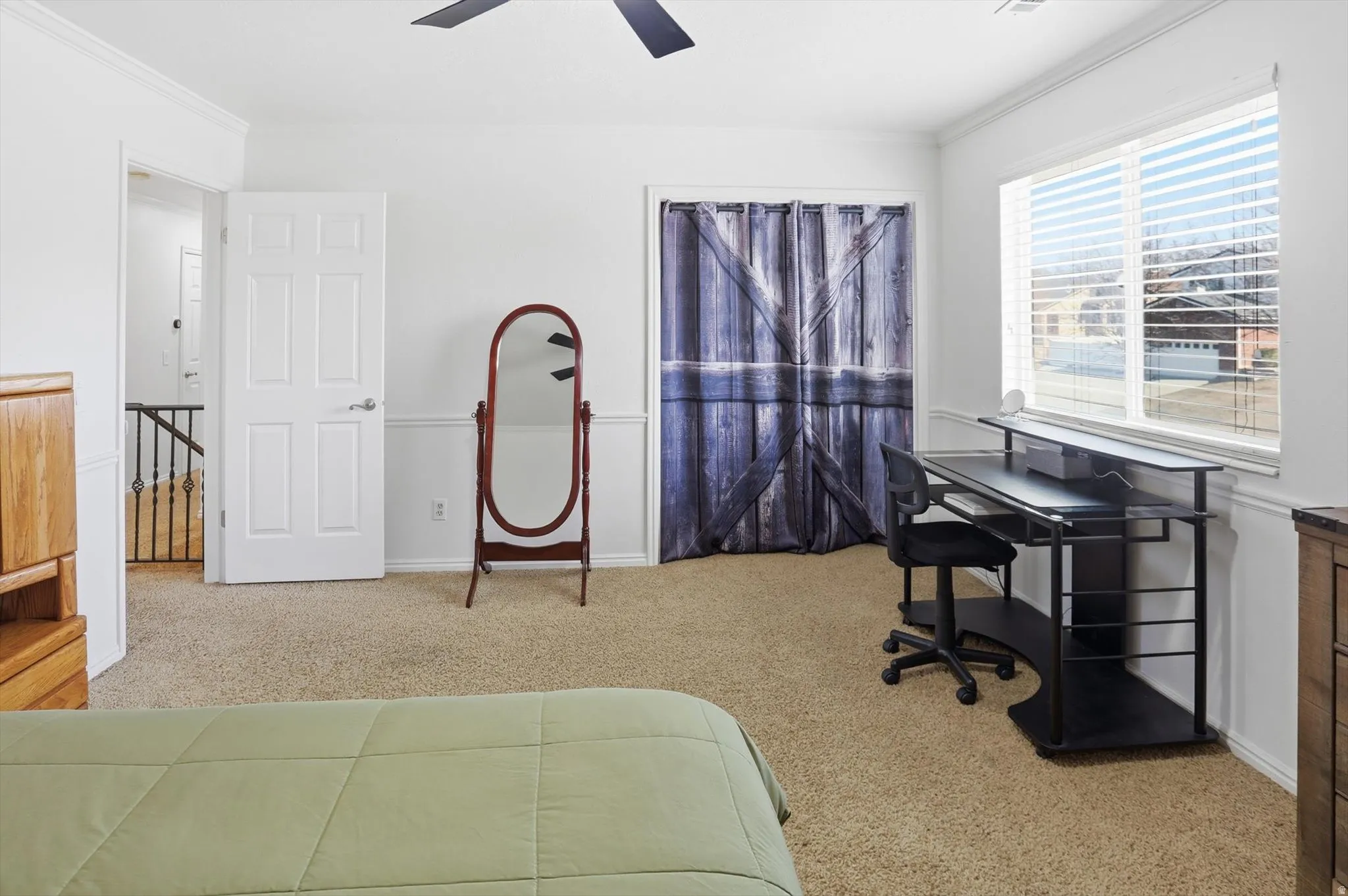 Bedroom with light colored carpet, crown molding, and a ceiling fan