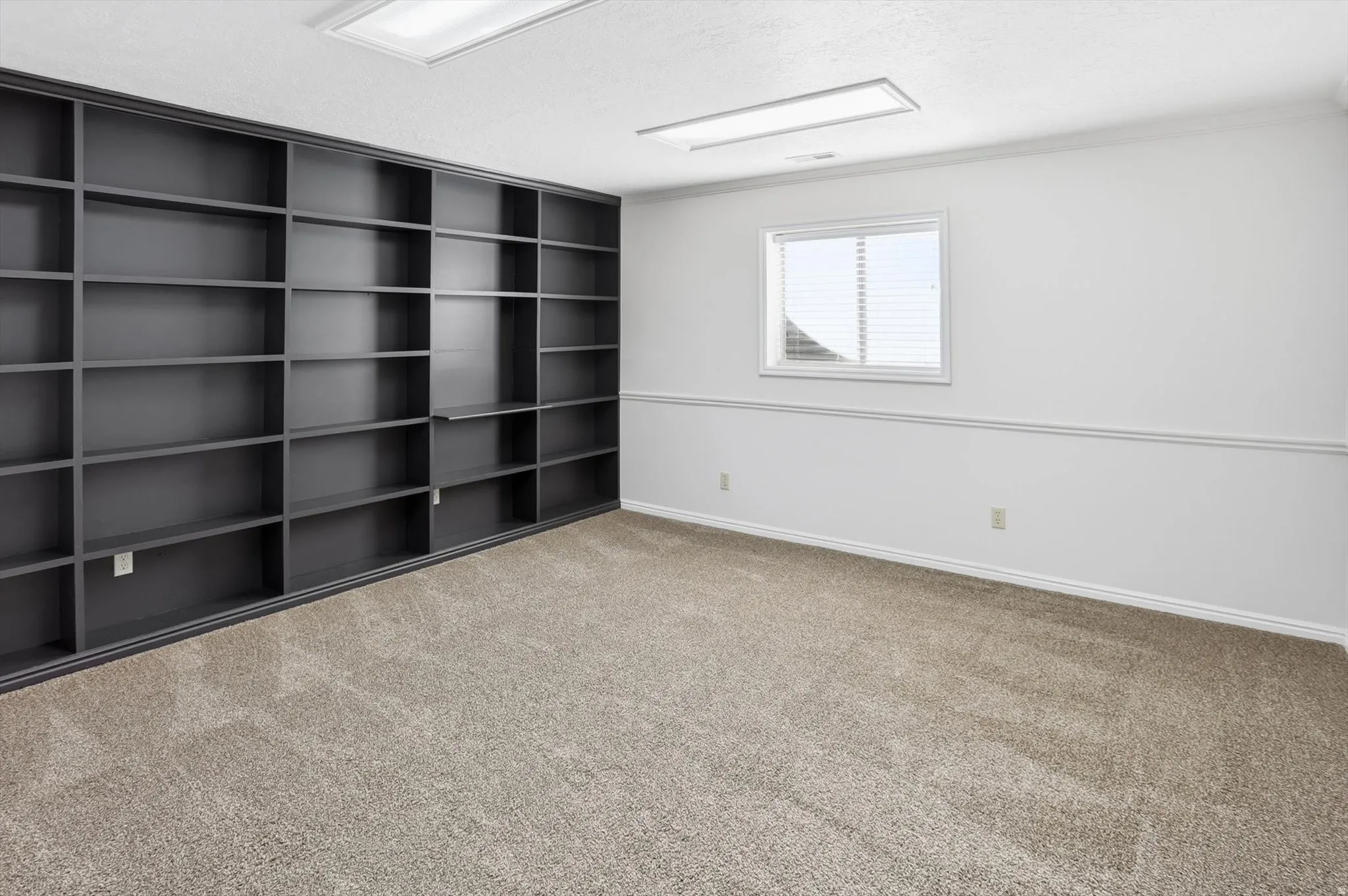 Unfurnished room featuring light carpet, a textured ceiling, and ornamental molding