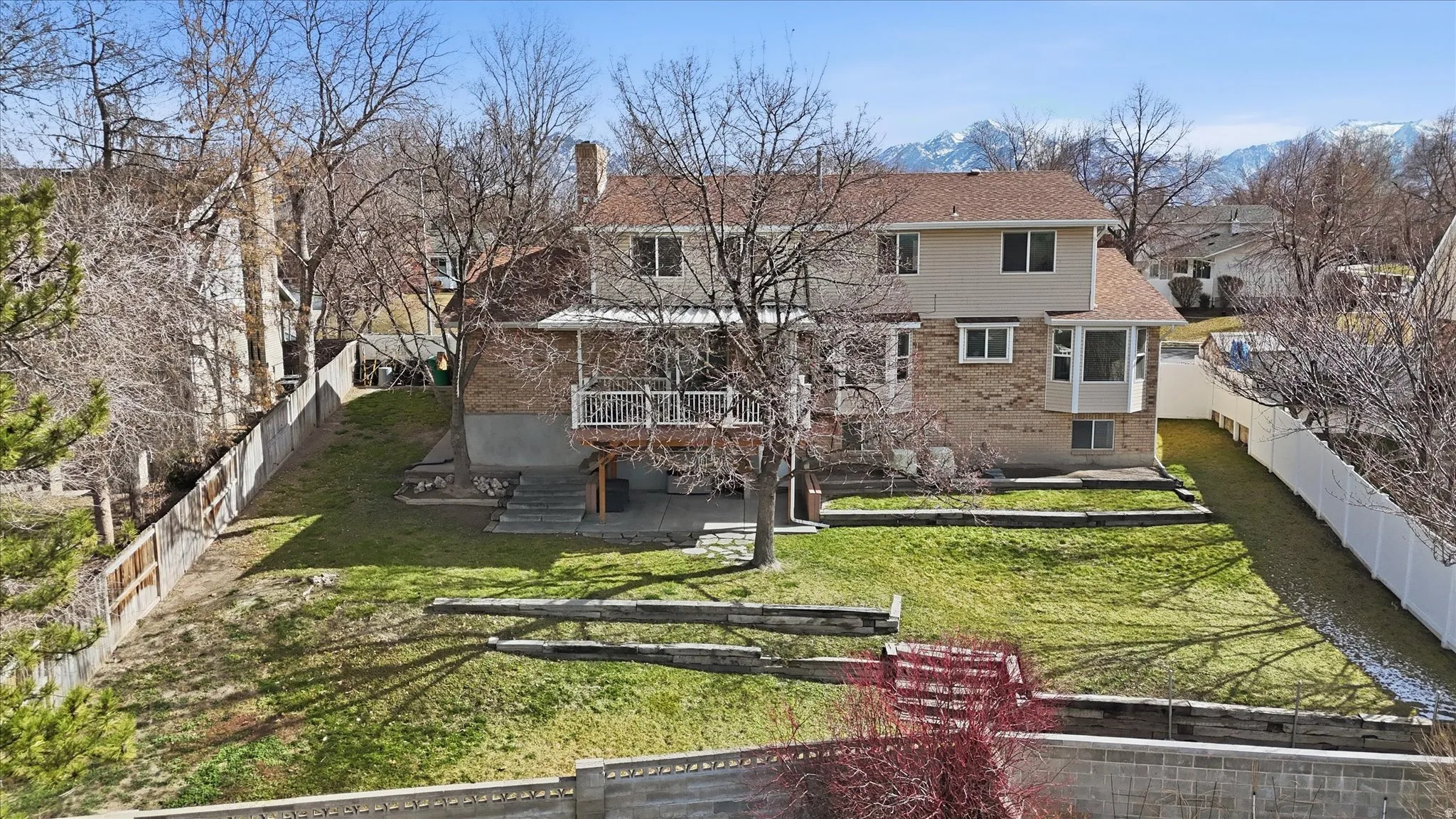 Rear view of property with a fenced backyard, brick siding, a patio, a chimney, and a deck