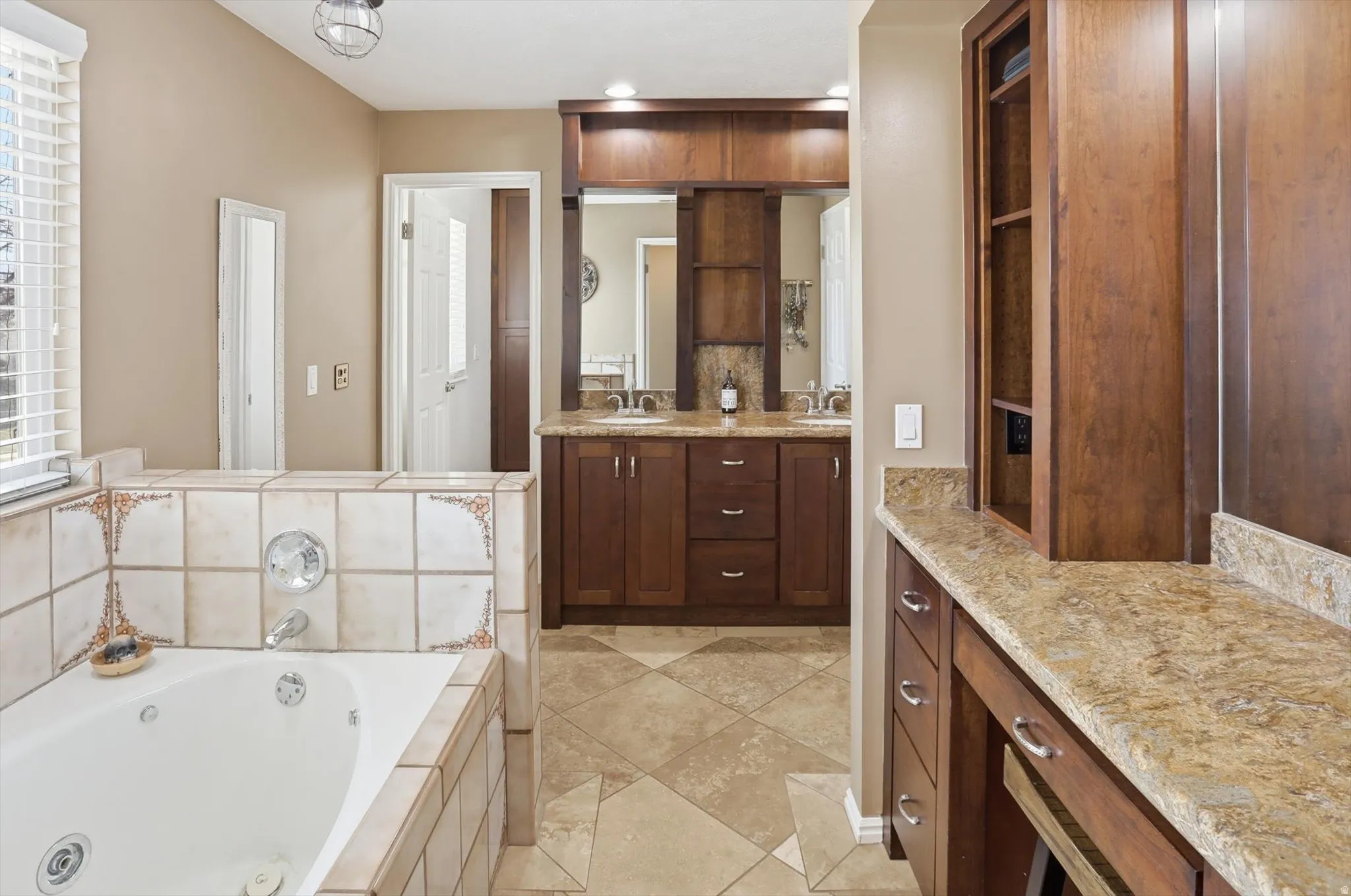 Bathroom featuring double vanity, a jetted tub, and light tile patterned floors