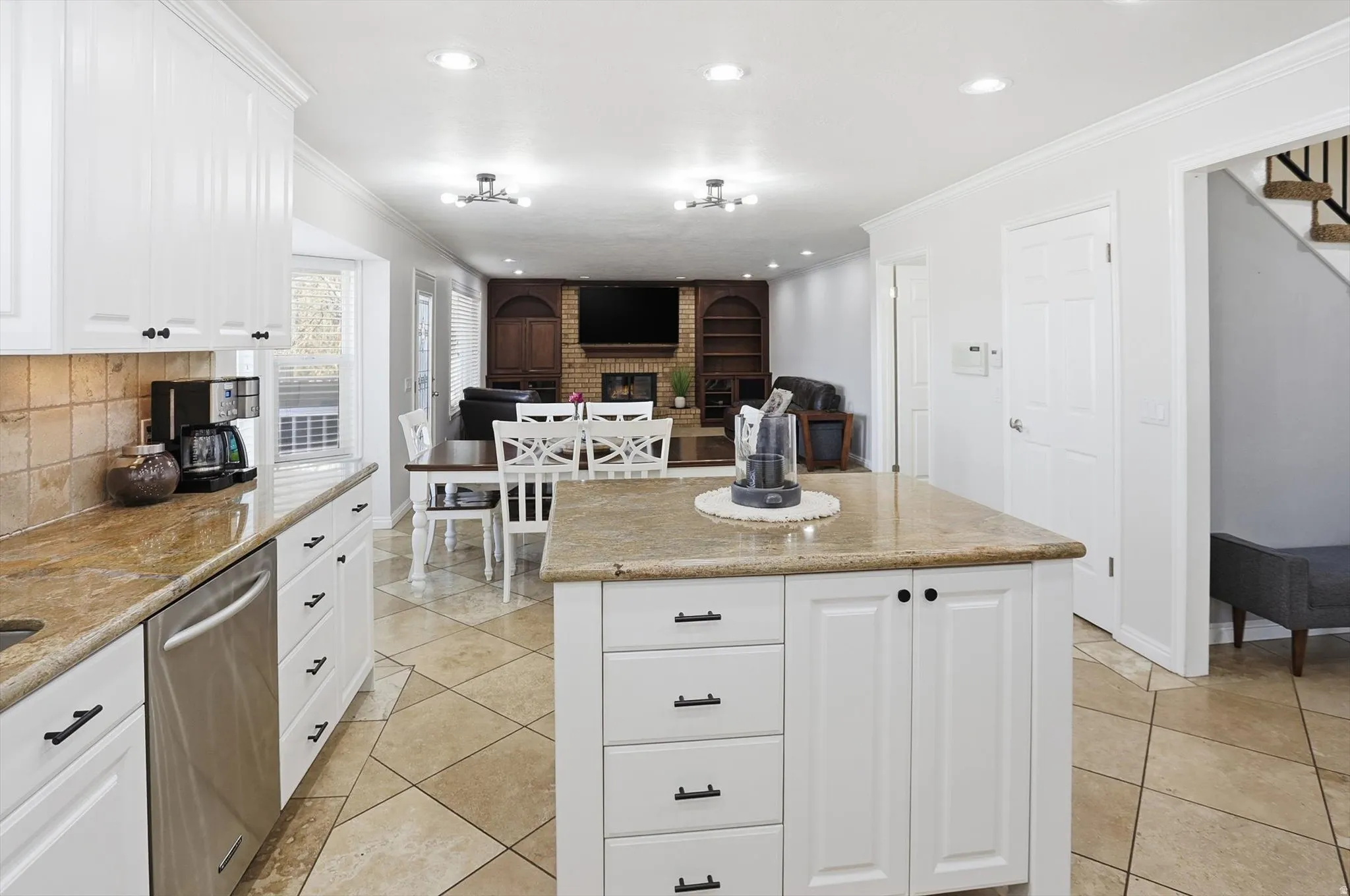 Kitchen with white cabinetry, tasteful backsplash, crown molding, a center island, and dishwasher