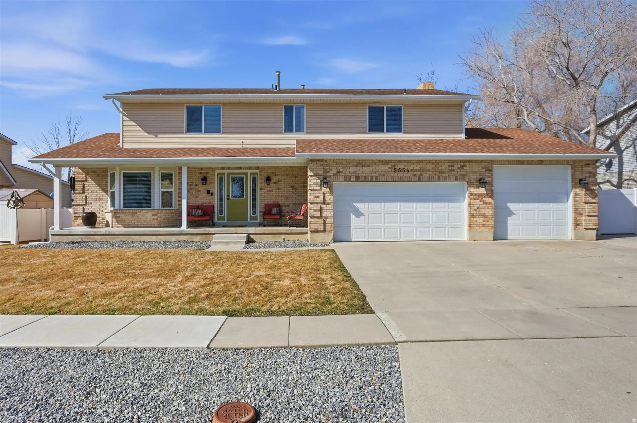 Traditional home with a porch, driveway, brick siding, a chimney, and a garage