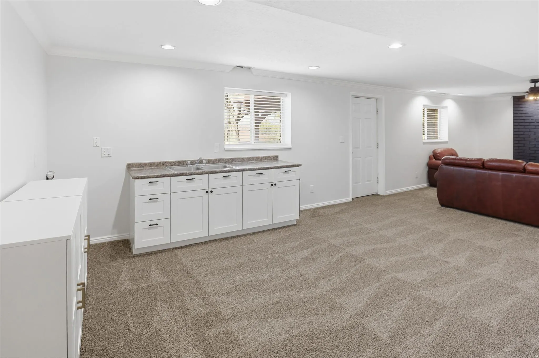Interior space featuring crown molding, white cabinets, light colored carpet, recessed lighting, and light countertops