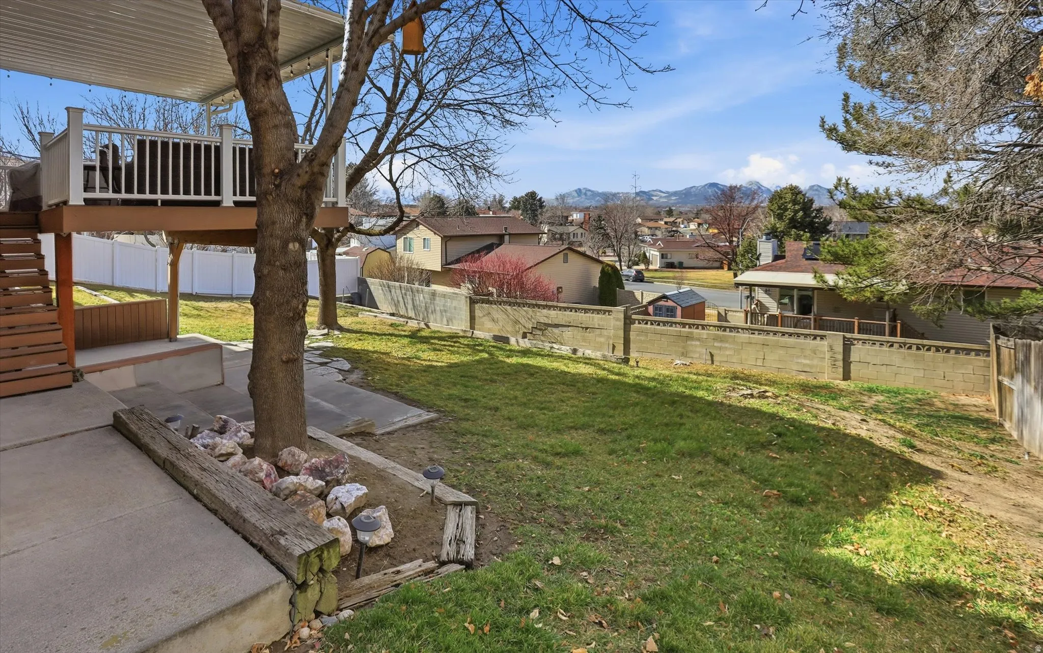 Fenced backyard featuring a patio area, a deck with mountain view, and a residential view
