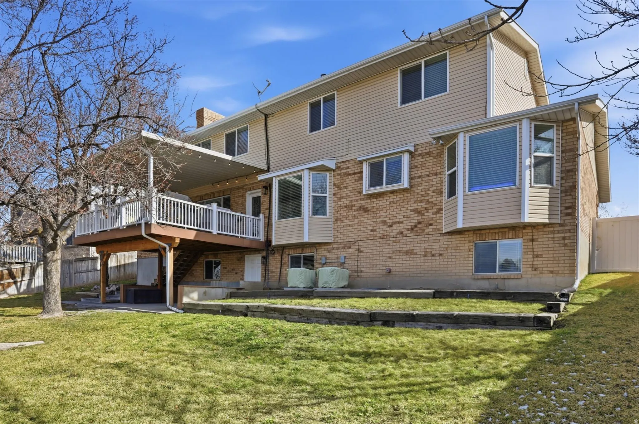 Back of house featuring brick siding, a patio, and a deck