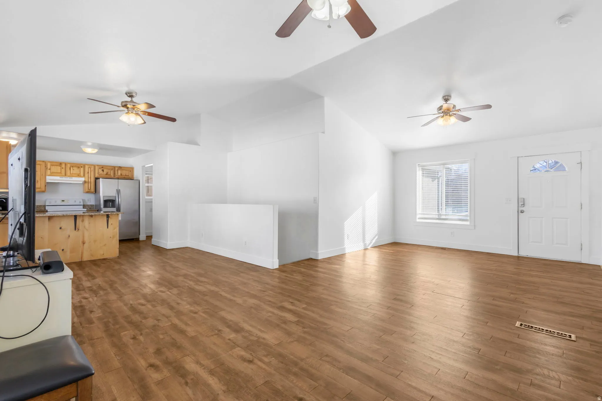 Unfurnished living room featuring ceiling fan, lofted ceiling, and dark wood-style flooring