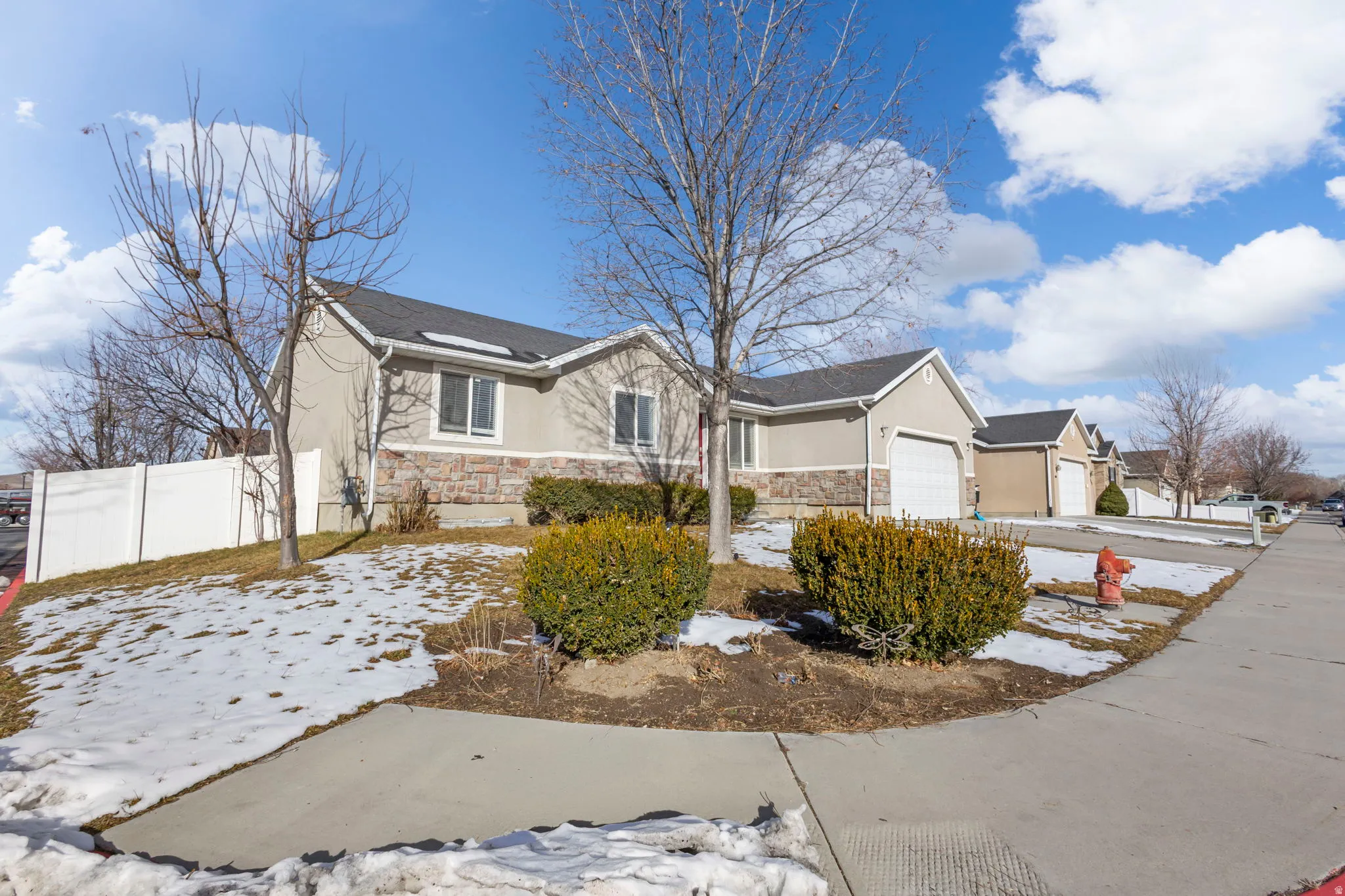 Ranch-style home featuring stone siding, stucco siding, and an attached garage