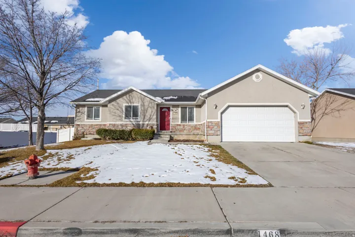 Ranch-style house with stone siding, a garage, driveway, and stucco siding