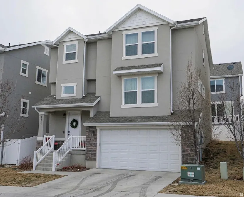 Traditional home featuring stucco siding, stone siding, a garage, concrete driveway, and covered porch