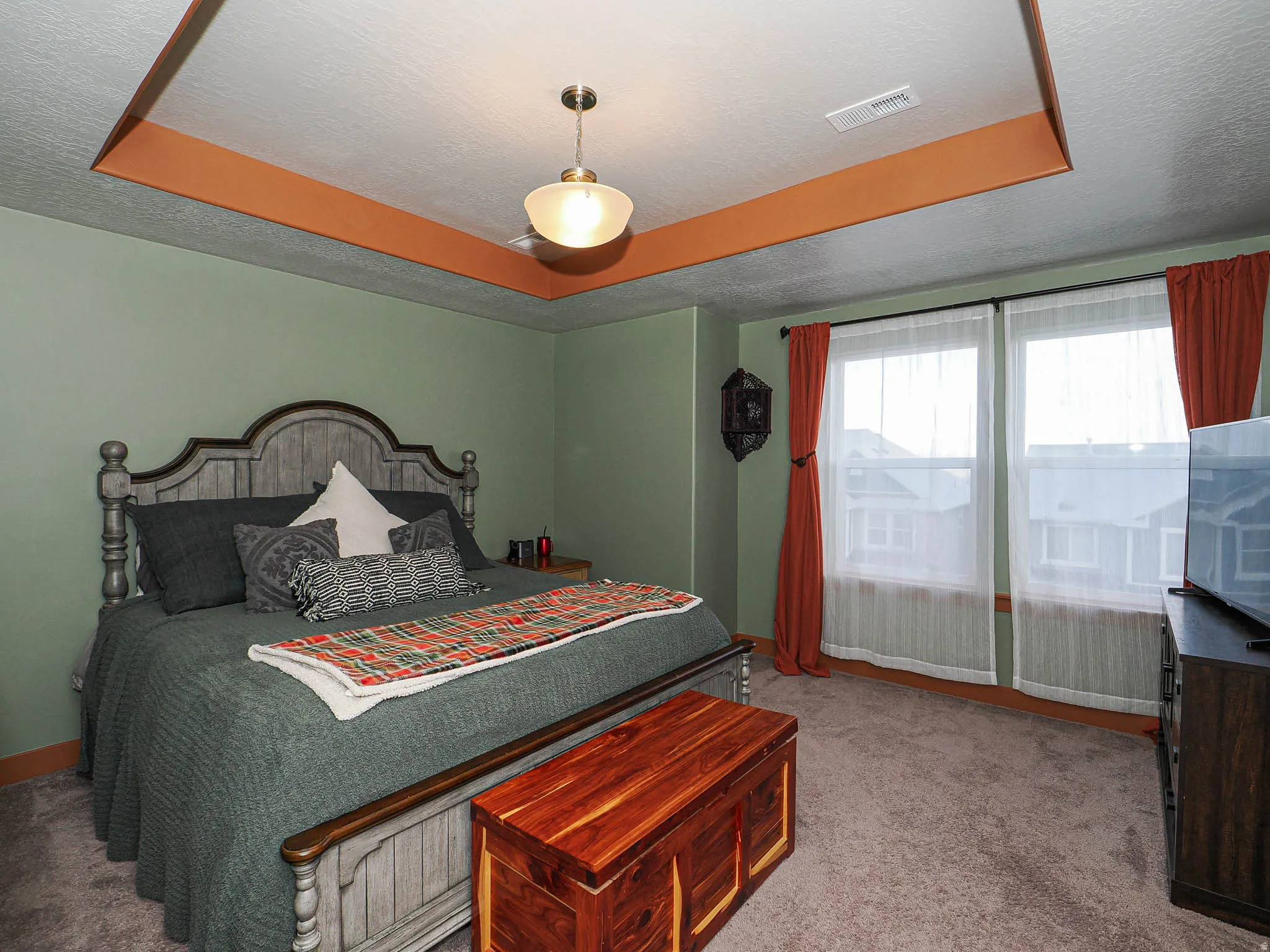 Bedroom with a tray ceiling, light colored carpet, and a textured ceiling