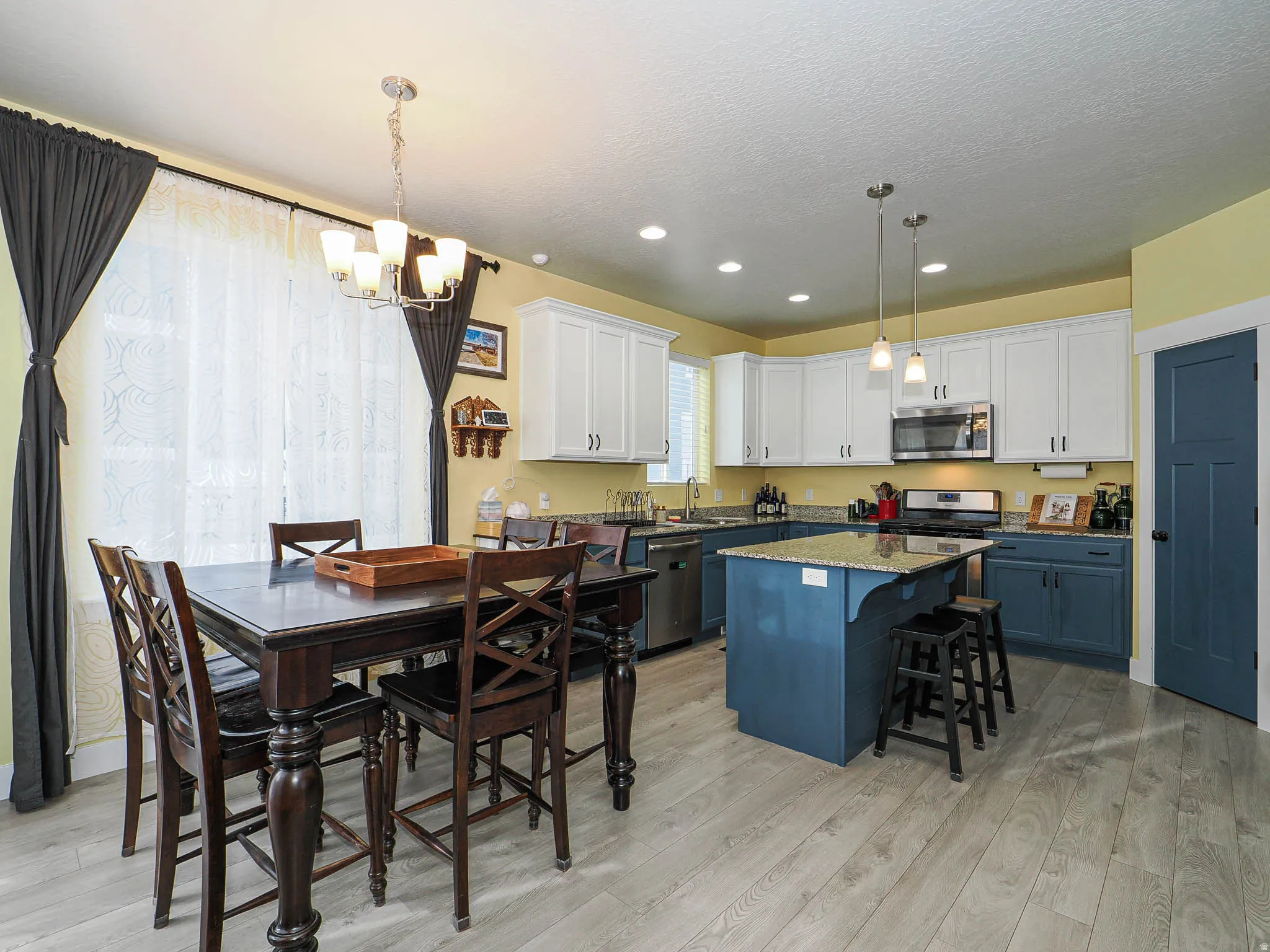 Kitchen featuring dual tone cabinets, a breakfast bar, dark stone countertops, stainless steel appliances, and a chandelier
