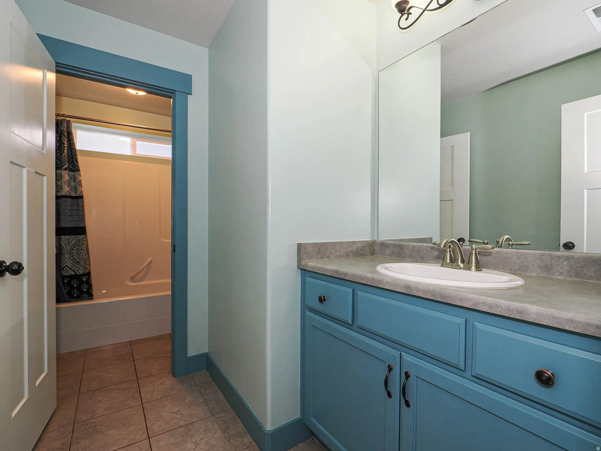 Full bathroom featuring vanity, light tile patterned floors, and shower / bath combo