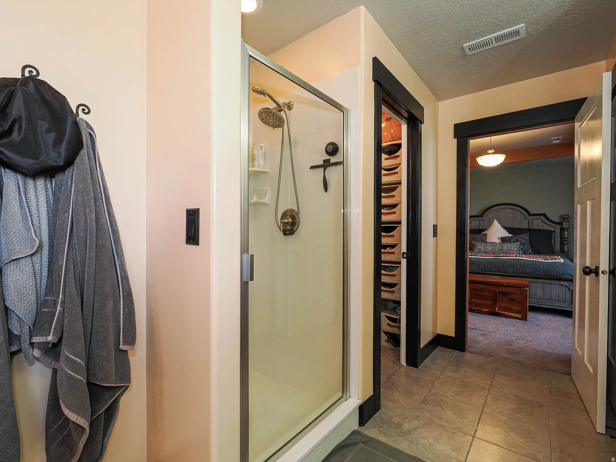 Ensuite bathroom with a stall shower, tile patterned floors, a textured ceiling, and a walk in closet