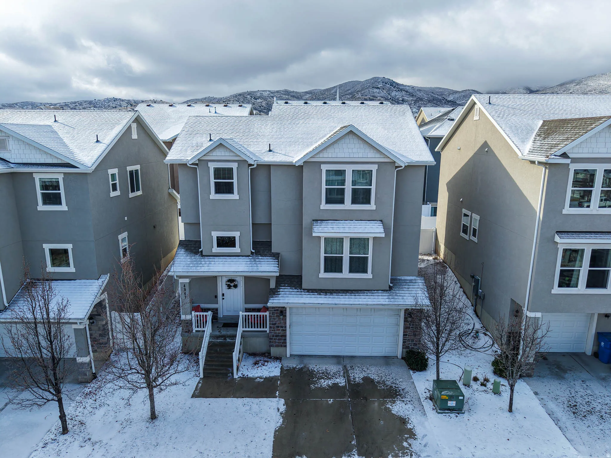 View of front of house with stucco siding, an attached garage, a residential view, a mountain view, and driveway