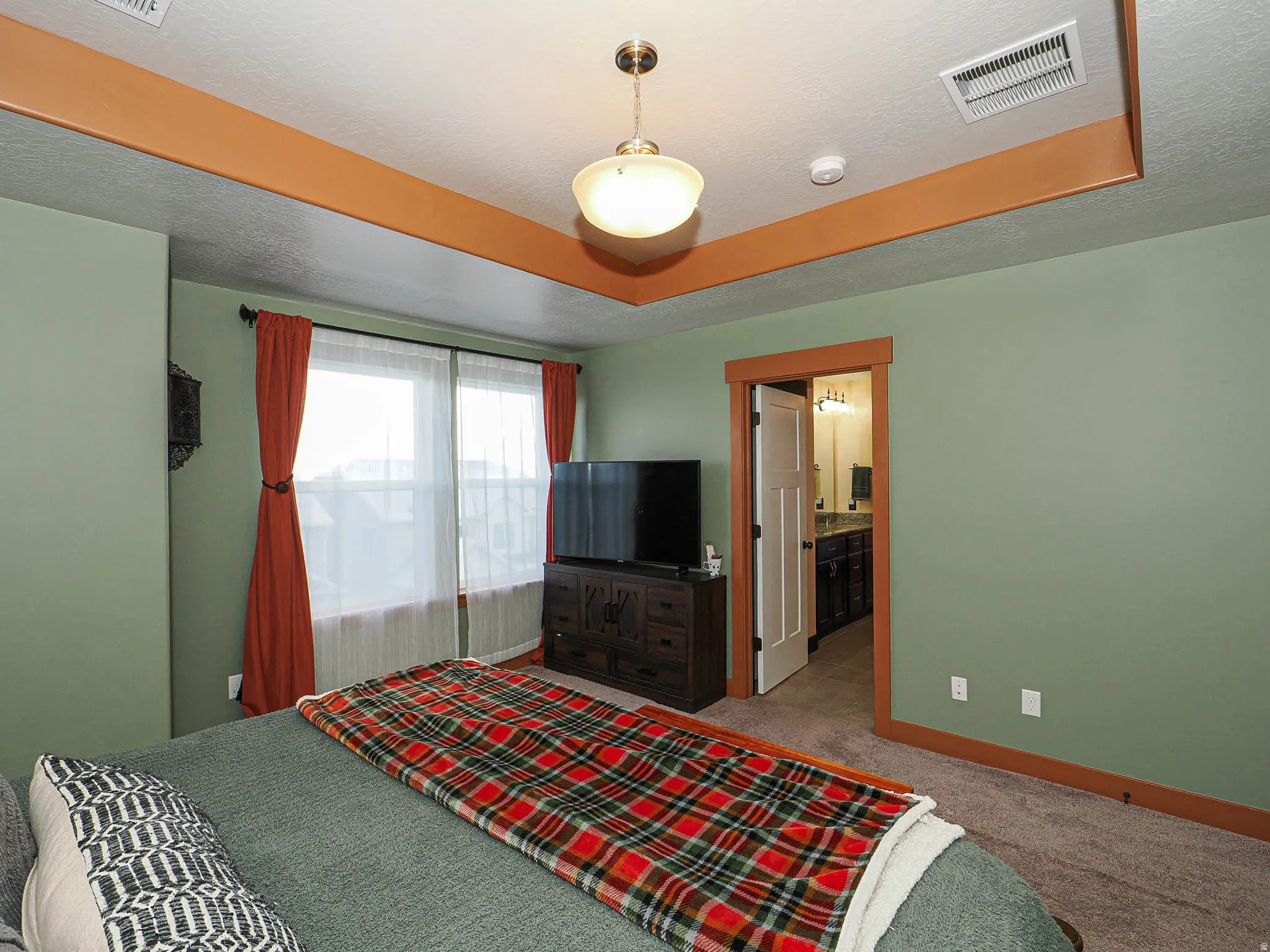Bedroom with carpet floors, ensuite bathroom, and a textured ceiling