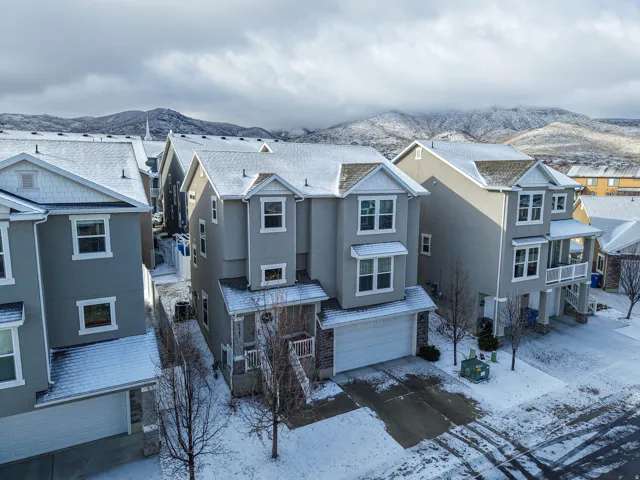 View of front of property with a mountain view, an attached garage, stucco siding, concrete driveway, and a residential view