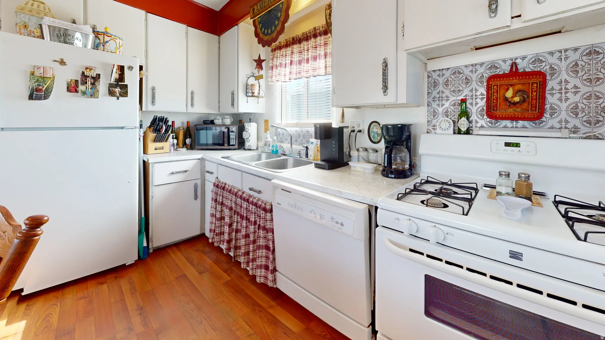 Kitchen featuring white appliances, light countertops, white cabinets, and light wood-style floors