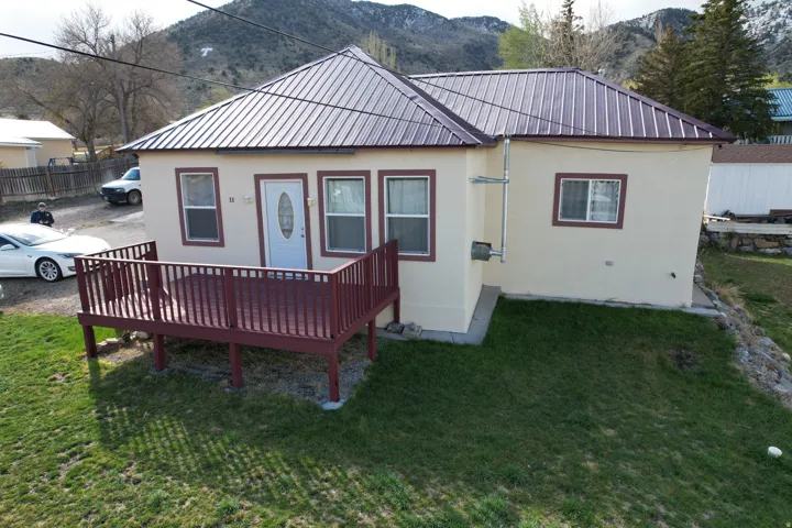 Back of house featuring a lawn, stucco siding, a deck with mountain view, and a metal roof