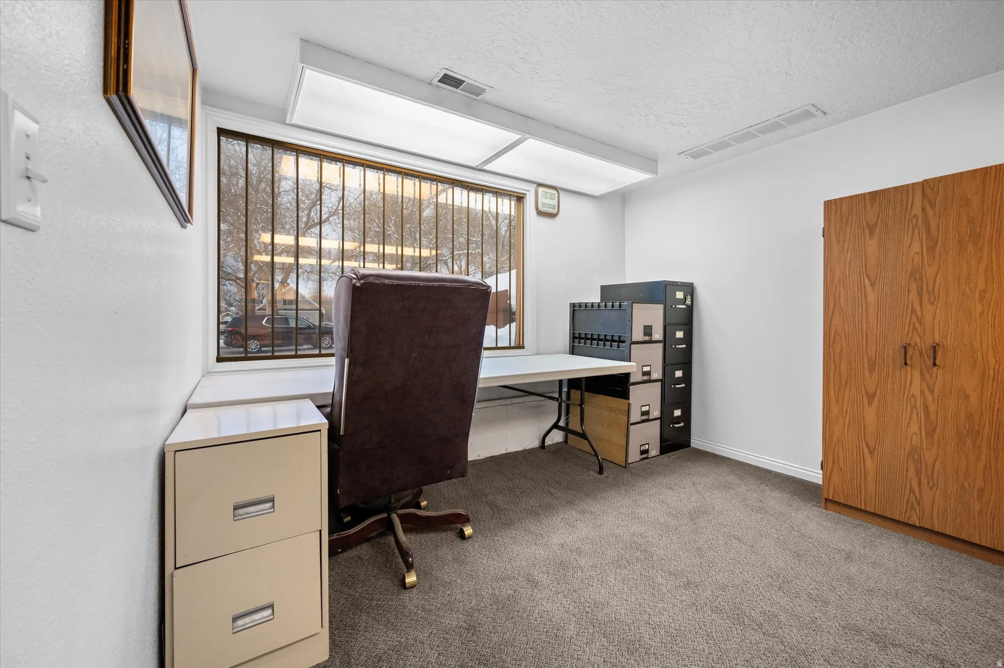 Extended area of office #2 featuring light colored carpet and a textured ceiling with a window  for natural light