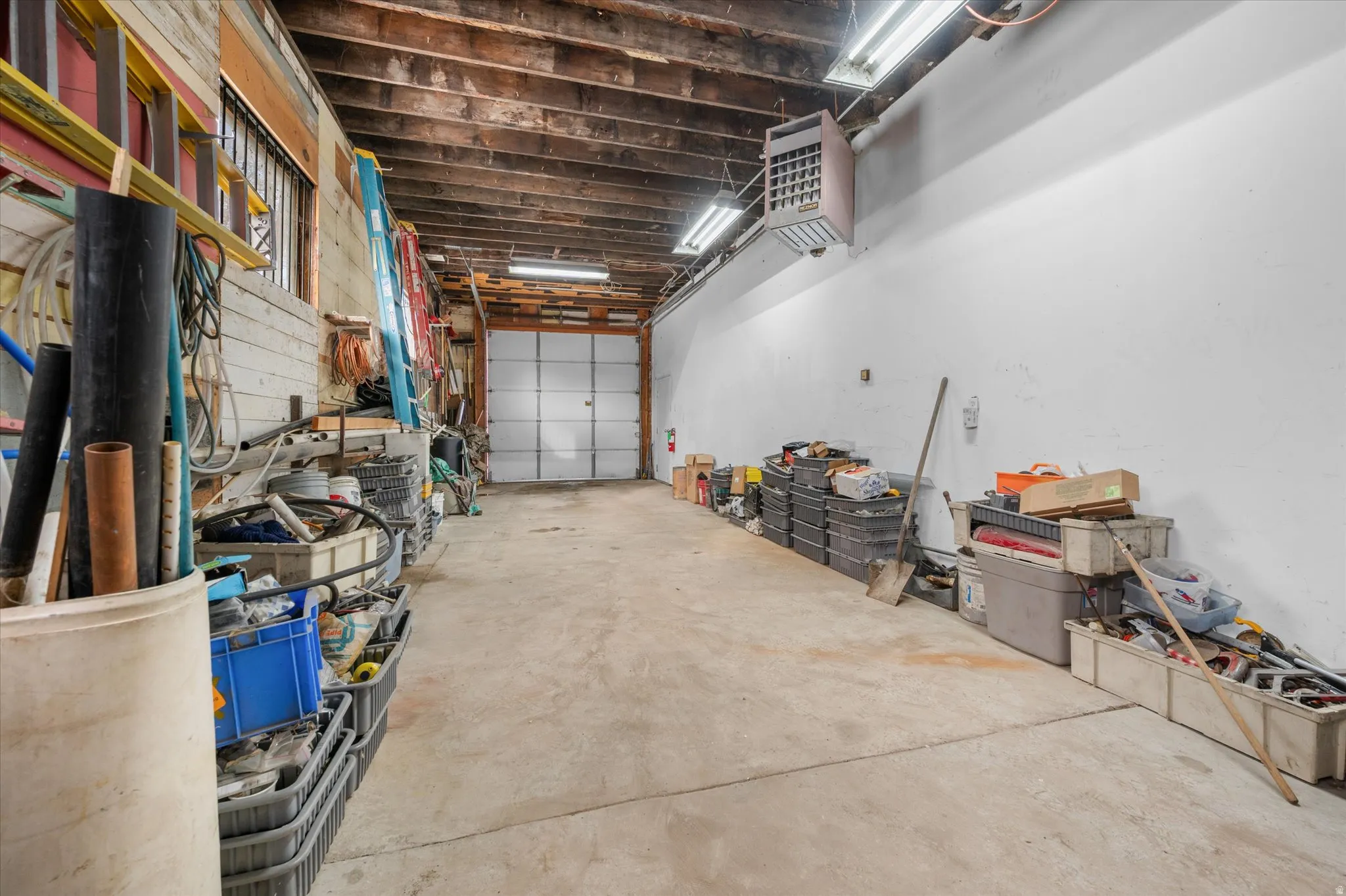 Garage with garage doors on both ends and access to office area and storage/supply area