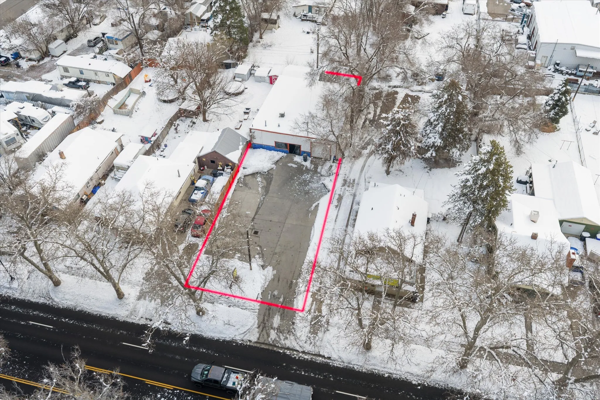 Snowy aerial view featuring  front property parcel outlined with large parking lot