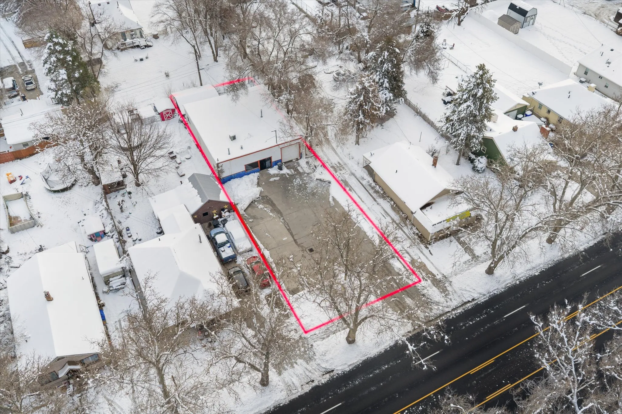 Aerial view with property parcel outlined with business and residential property surrounding it