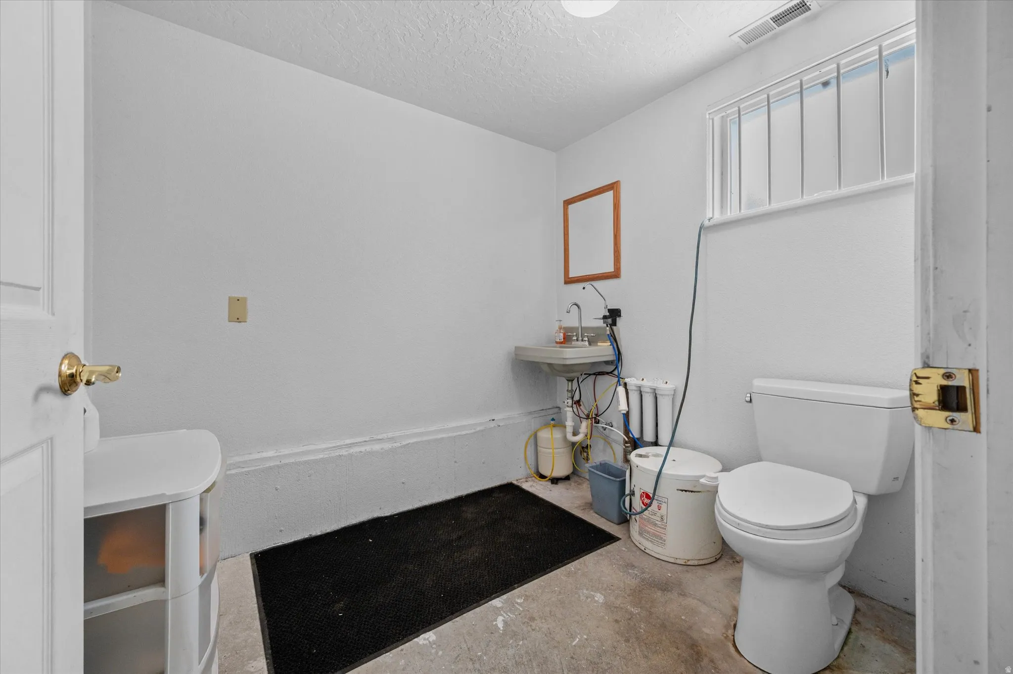 Half bathroom with concrete flooring and storage area