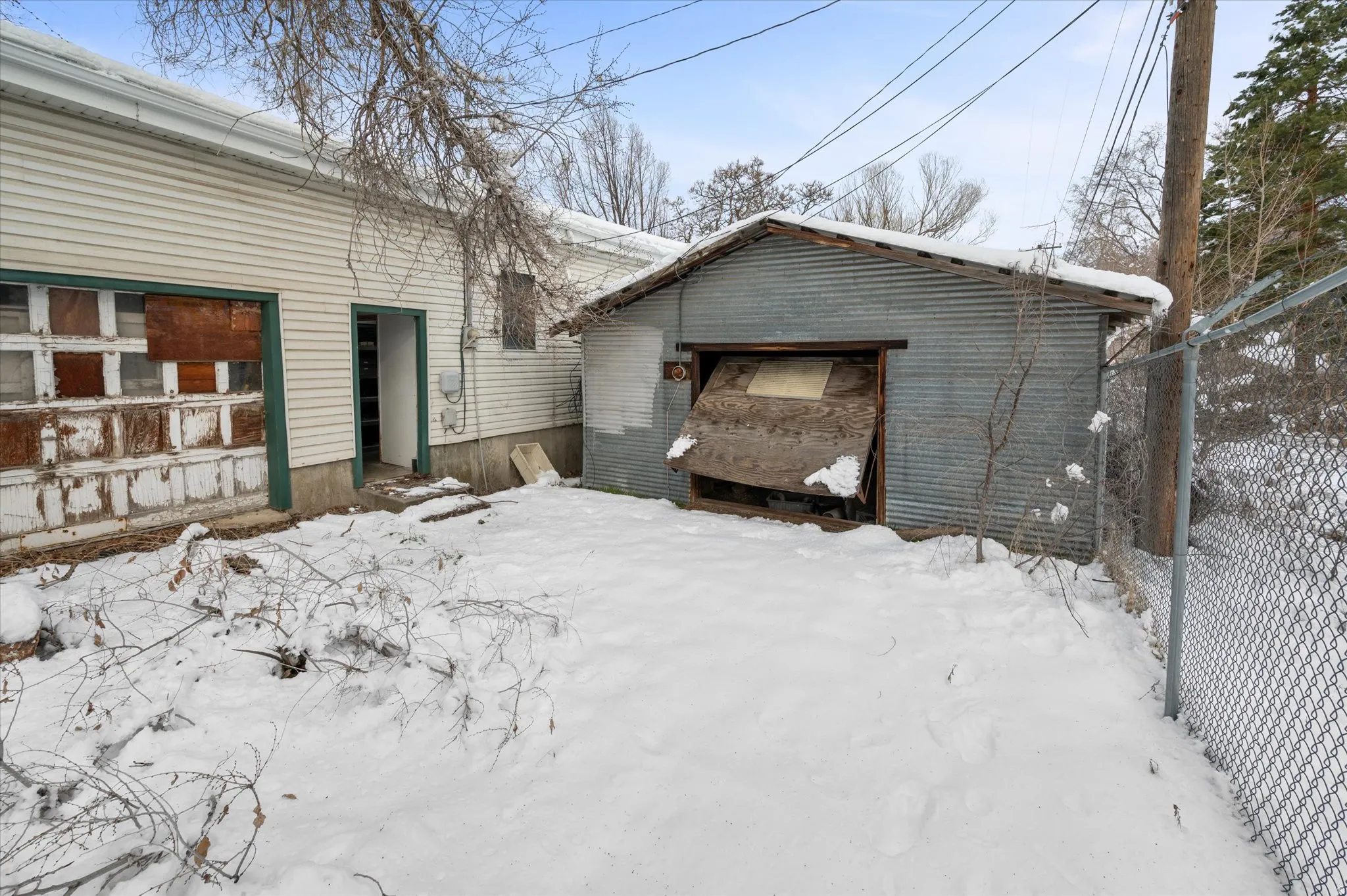 Back of building with garage access, storage room access, and an additional garage for storage or extra parking