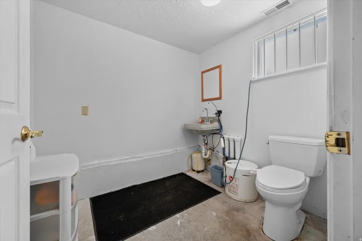 Half bathroom with concrete flooring and storage area