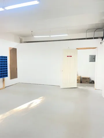 Spacious open studio with polished concrete flooring, recessed and linear ceiling-mounted lighting, and white painted walls