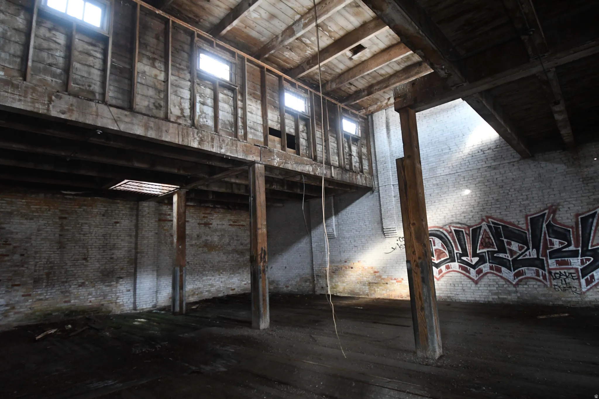 Misc room with brick wall, dark wood-style flooring, and a high wooden ceiling