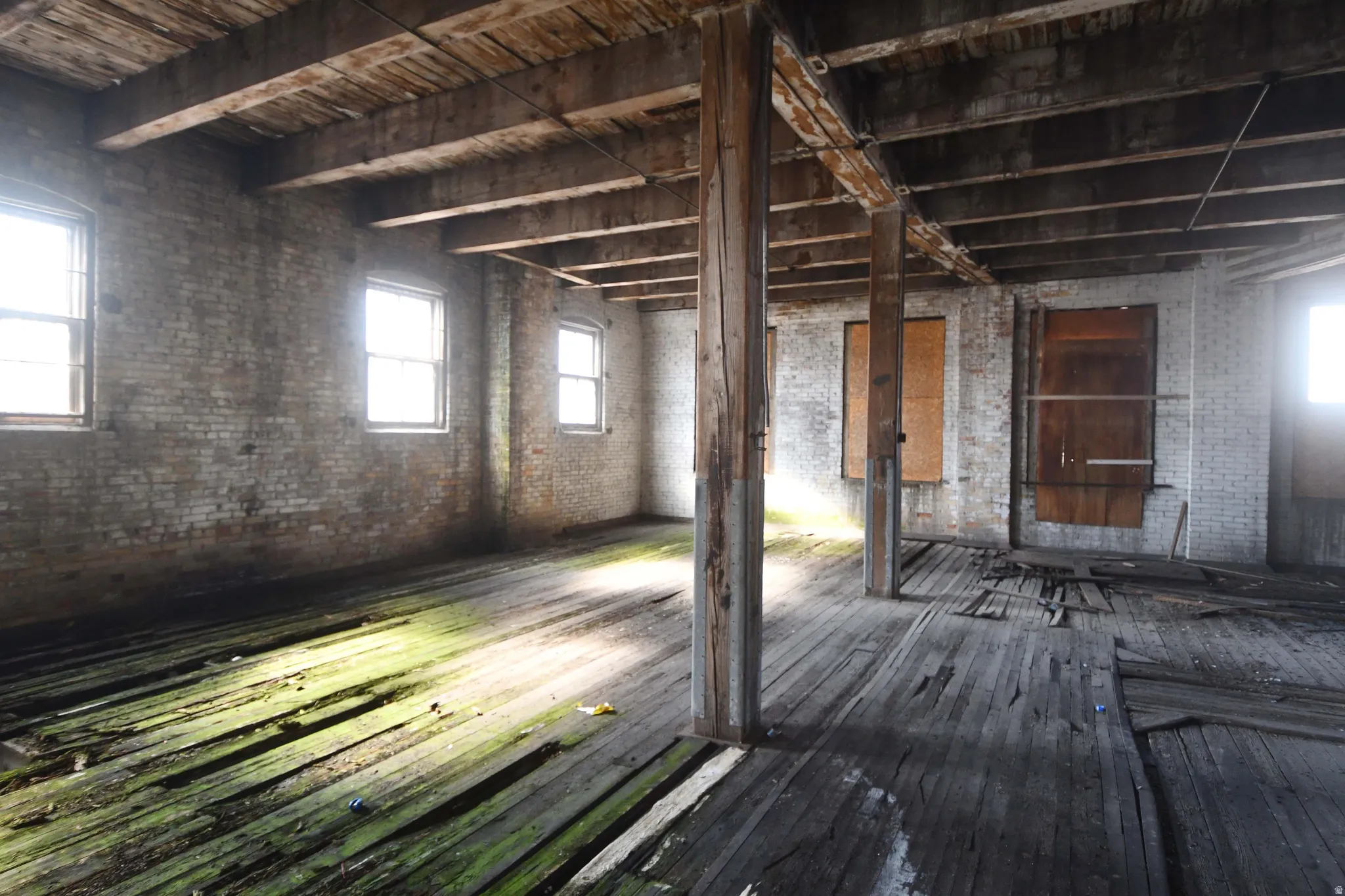 Misc room featuring brick wall and dark wood finished floors