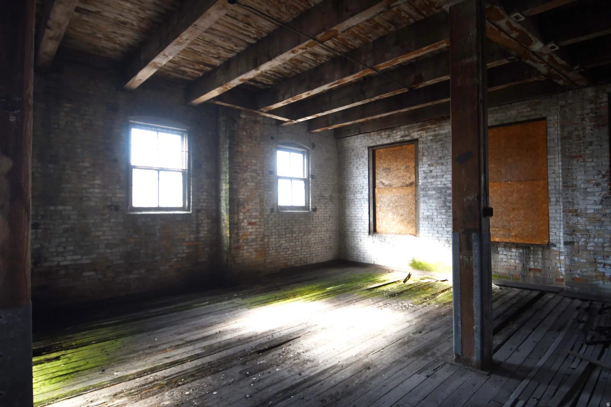 Misc room featuring dark wood-style floors, brick wall, and beamed ceiling