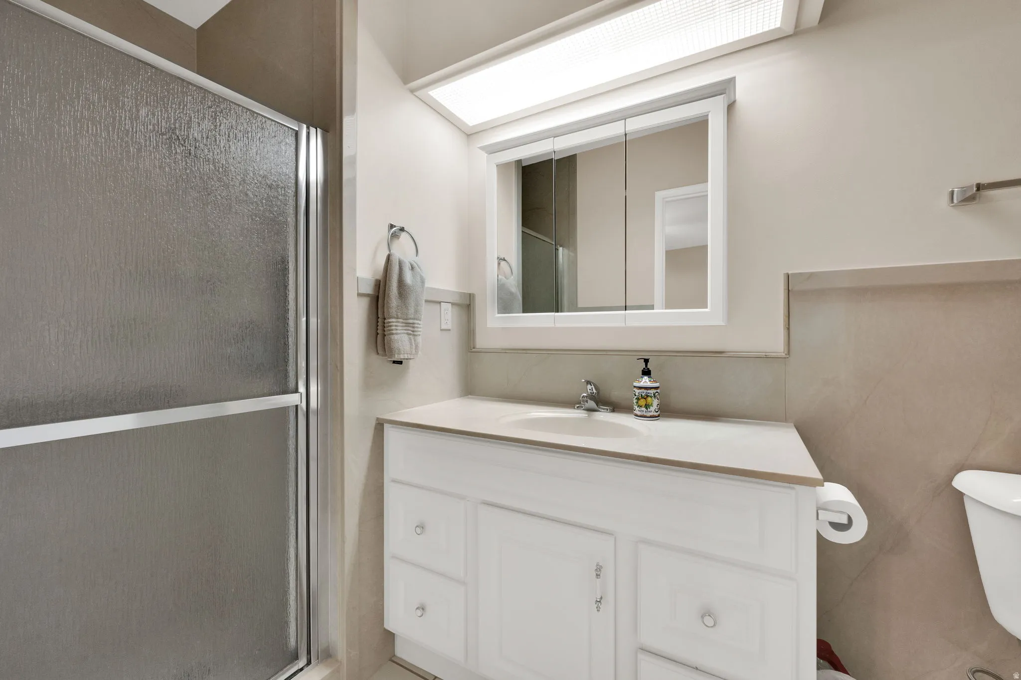Full bathroom featuring a shower stall, vanity, and tile walls