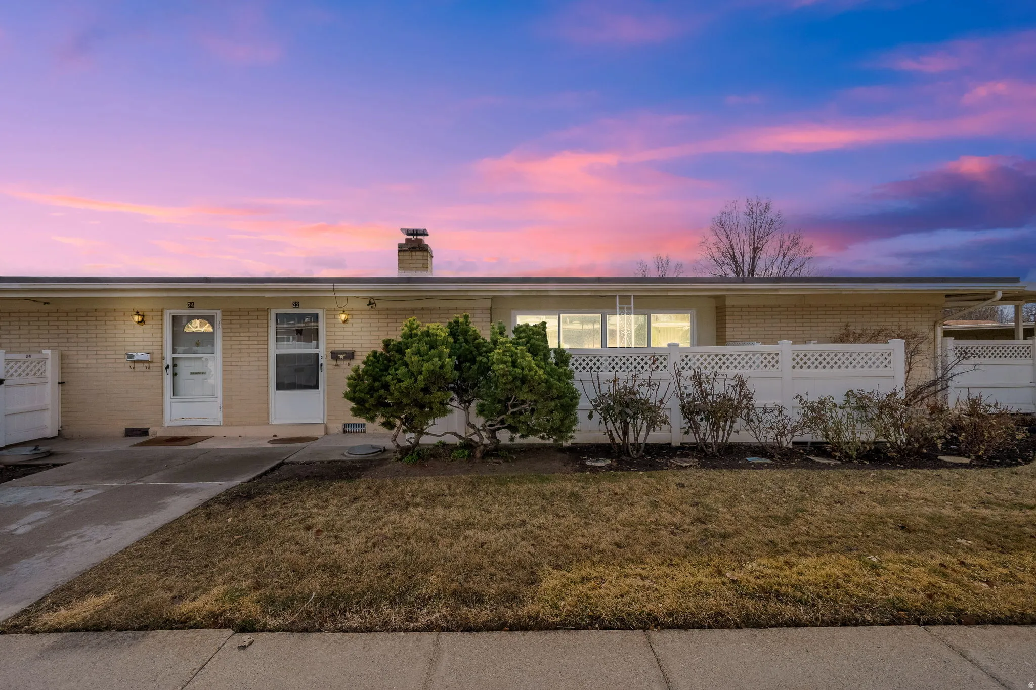 Ranch-style home featuring brick siding, a chimney, an attached carport, and driveway