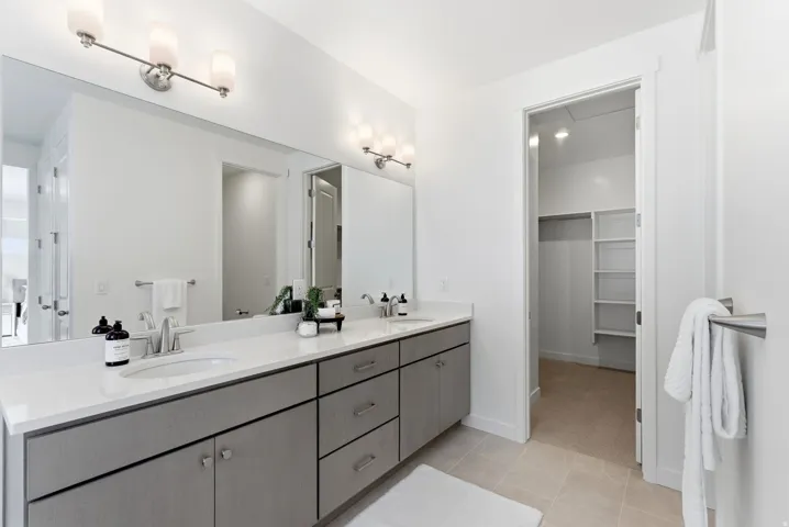 Full bath with double vanity, a spacious closet, and light tile patterned floors