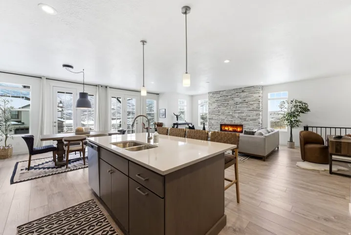 Kitchen featuring dark wood finish cabinetry, light wood-style floors, pendant lighting, and a stone fireplace