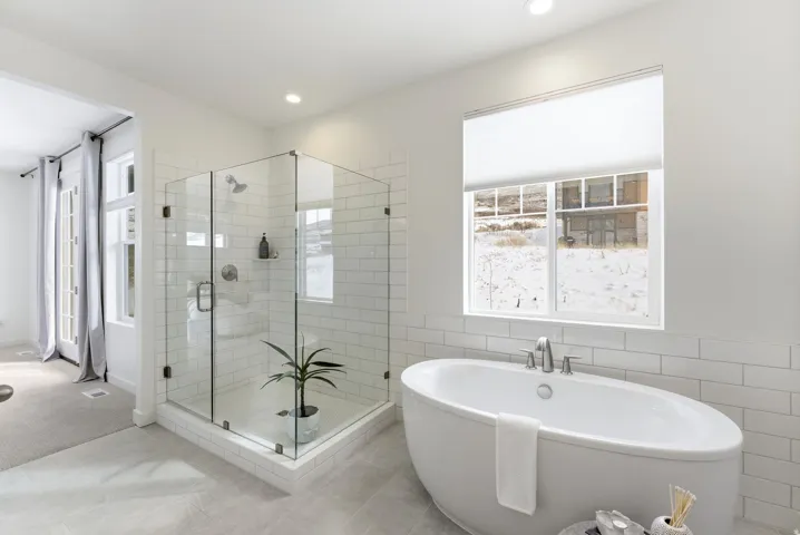Bathroom featuring a shower stall, a freestanding bath, tile walls, and a wainscoted wall