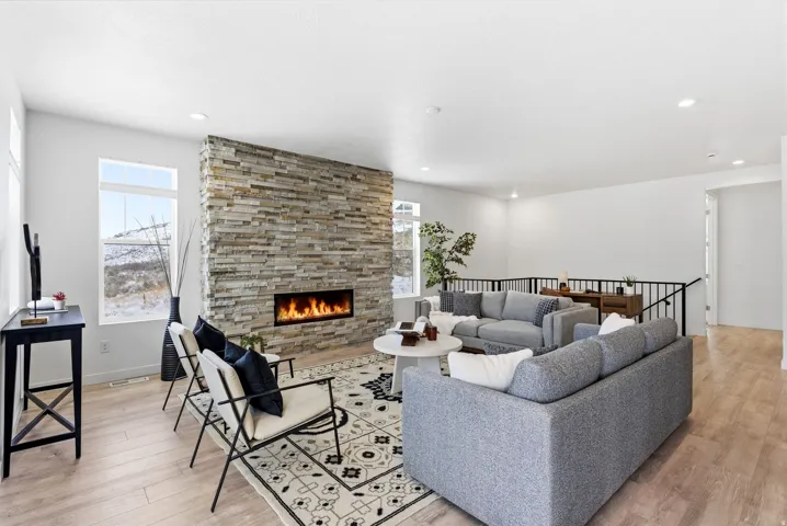 Living area featuring light wood-style floors and a stone fireplace
