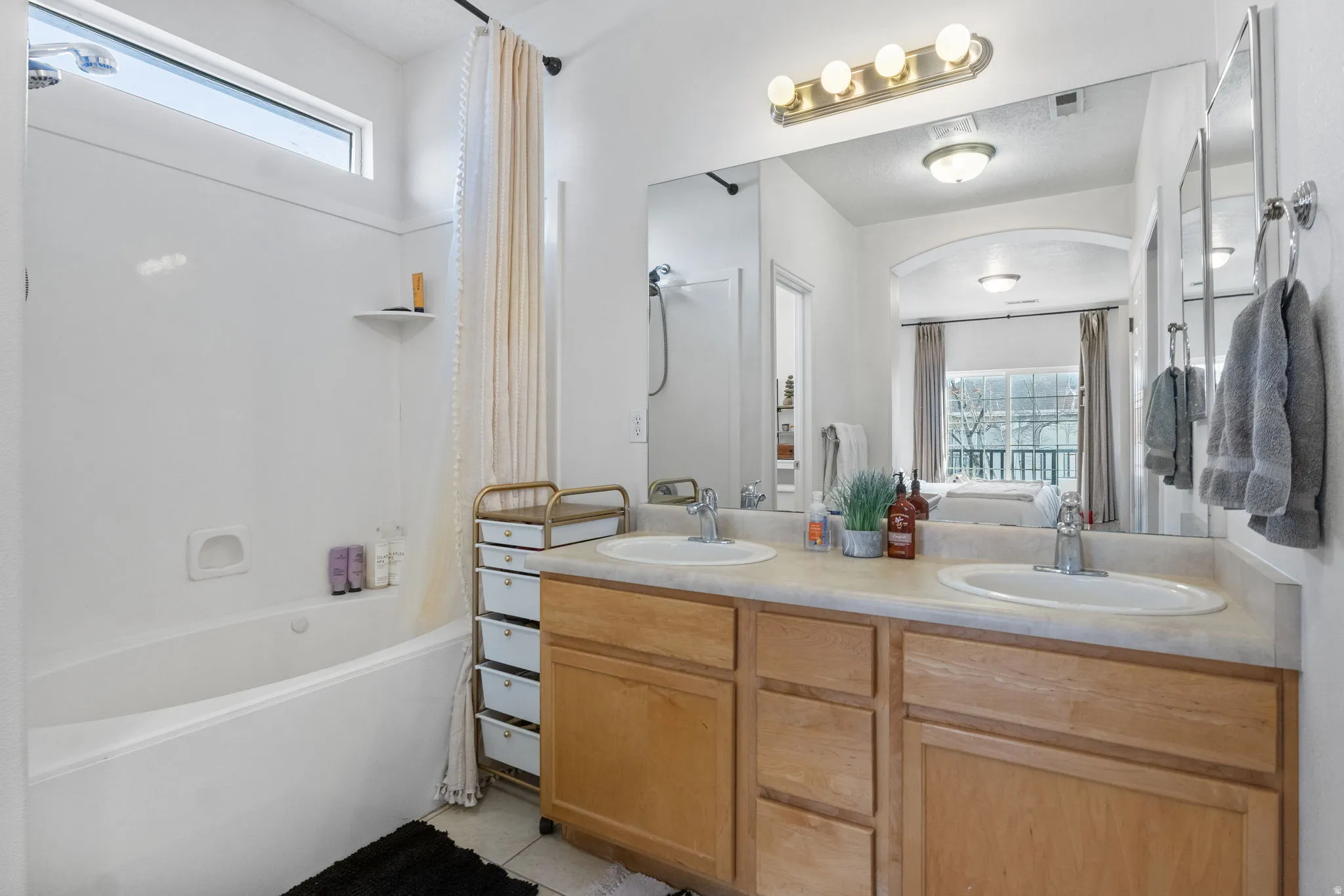 Ensuite bath featuring double vanity, shower / bath combination with curtain, ensuite bath, and light tile patterned flooring