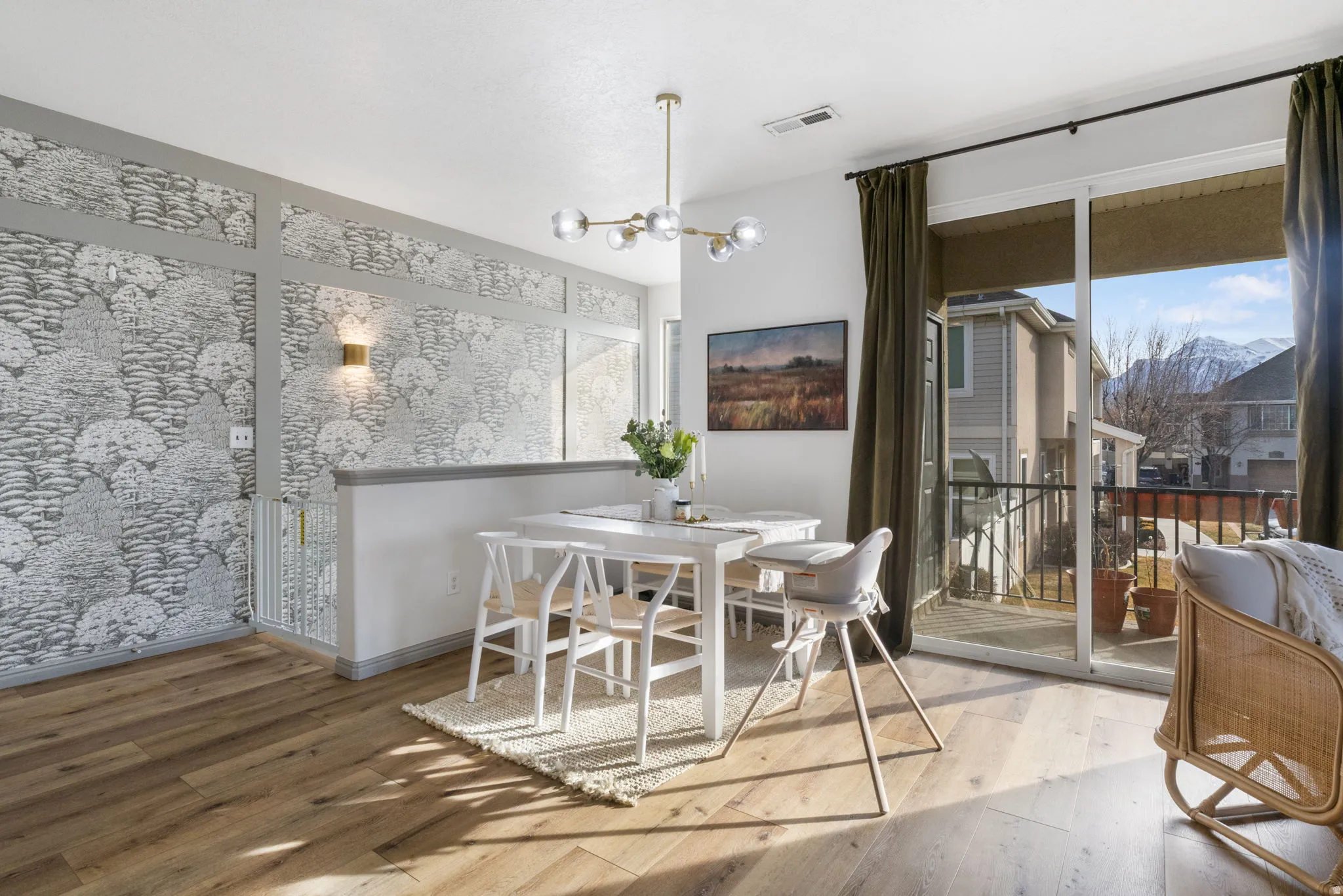 Dining area featuring hardwood / wood-style floors, an accent wall, suspended lighting, and wallpapered walls