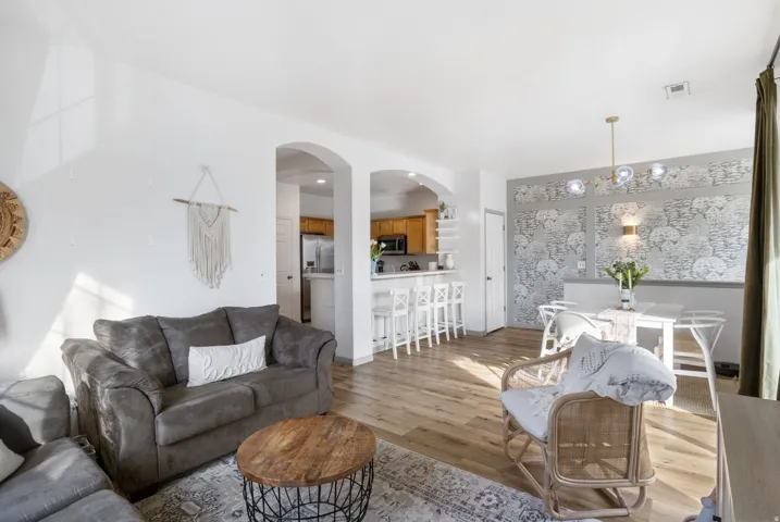 Living area featuring light wood-type flooring, arched walkways, and suspended lighting
