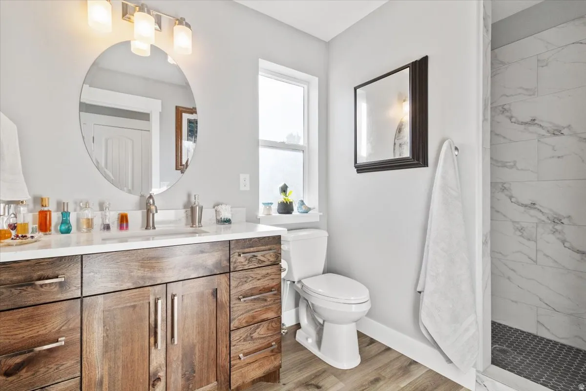 Full bath featuring vanity, a marble finish shower, and light wood-style floors