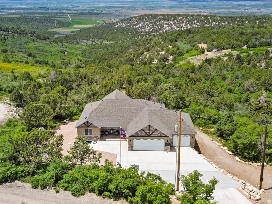 Aerial view of property and surrounding area featuring a heavily wooded area and mountains