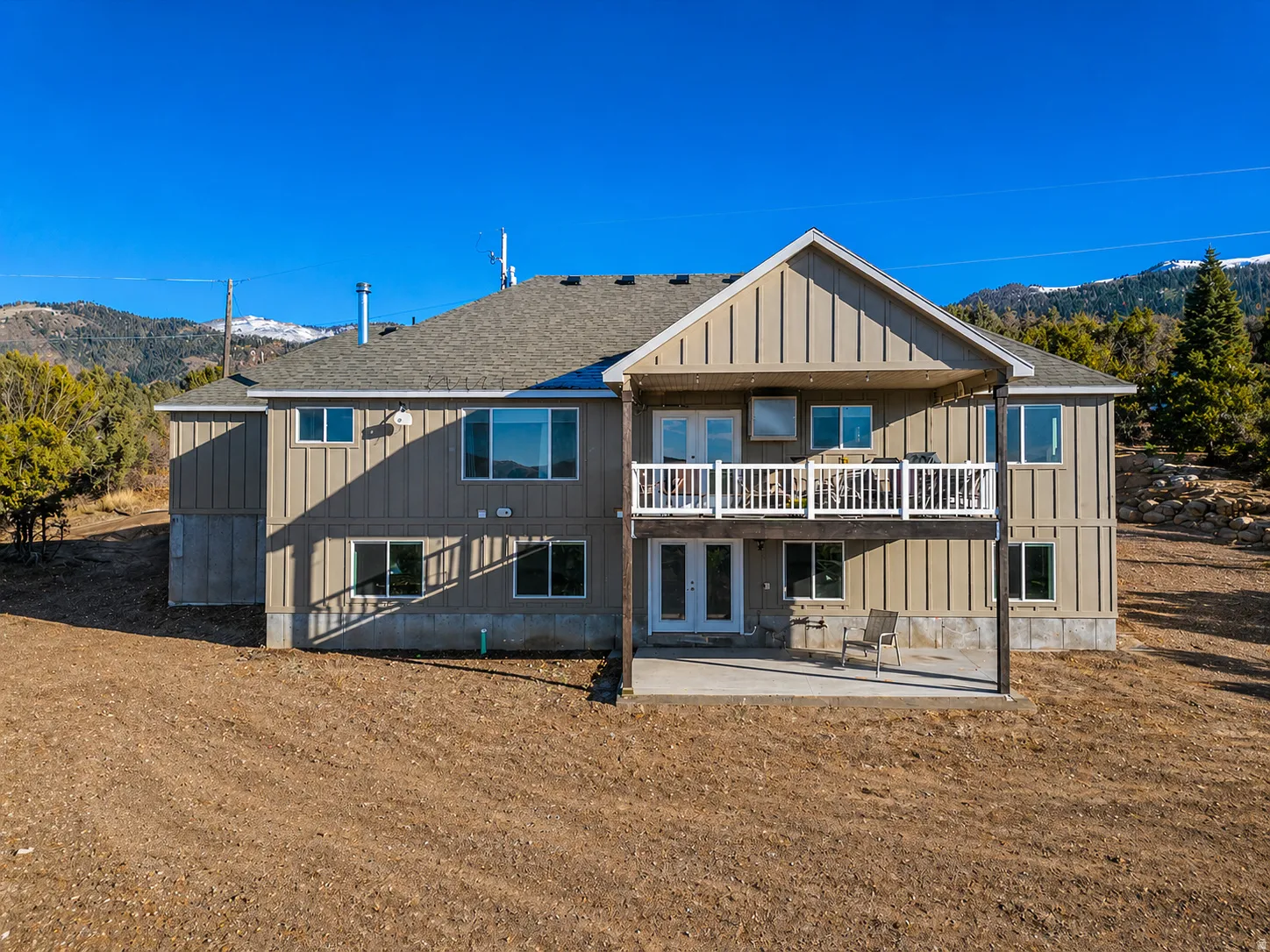 Rear view of property featuring a patio area, a shingled roof, a balcony, board and batten siding, and a mountain view