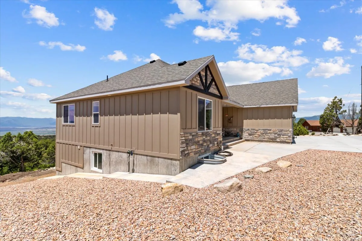 View of property exterior featuring a shingled roof, a mountain view, stone siding, and board and batten siding